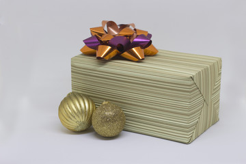 Gift box with an orange bow and two golden balls on a white background, Christmas composition