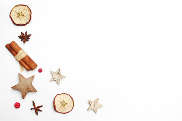 Wall Mural - Christmas festive styled stock image composition. Decorative pattern. Cinnamon sticks, red berries, dried apple fruit, anise and wooden stars isolated on white wooden background. Flat lay, top view.