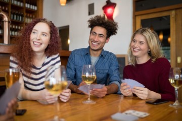 Wall Mural - Happy friends playing cards while having glass of beer