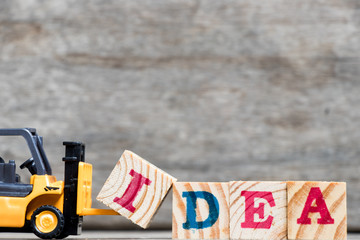 Wall Mural - Yellow plastic forklift hold letter I to complete word idea on wood background