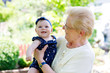 © Irina Schmidt - Cute little baby girl with grandmother on summer day in garden
