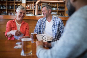 Wall Mural - Happy friends playing cards while having glass of beer