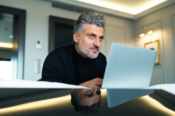 Wall Mural - Mature businessman with laptop in a hotel room.