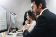 © SFIO CRACHO - Two young business professionals working process at office.Young professionals work with new market project on desktop computers. Blurred background.Horizontal.
