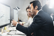© SFIO CRACHO - Two business person at working process at office.Young professionals work with new market project on desktop computers. Blurred background.Horizontal.