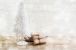 © Maren Winter - small christmas tree from white wire and gifts in kraft paper on a rustic wooden table, white painted vintage background with snowy bokeh lights, copy space