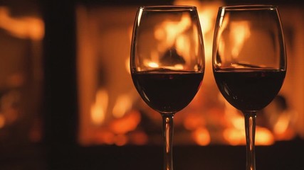 Wall Mural - Cinemagraph - Two red wine  wineglasses over fireplace background. Motion Photo.