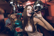 © VadimGuzhva - Young people have fun in a nightclub and sing in karaoke. In the foreground is a woman in a beige dress.
