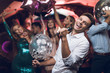 © VadimGuzhva - Young people have fun in a nightclub and sing in karaoke. In the foreground is a man in a white shirt.