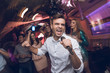 © VadimGuzhva - A man in a white shirt is singing in a nightclub. He has a microphone in his hands.