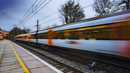 Wall Mural - Commuter train departing a station at dusk