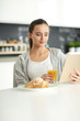 © lenets_tan - Young woman with orange juice and tablet in kitchen.