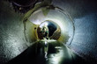 Sewer tunnel worker in special chemical protective suite in underground sewer tunnel examining sewage collector