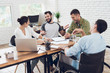 © VadimGuzhva - A group of young people discussing business while working in the office.