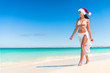 © Maridav - Christmas cruise travel beach vacation holidays in Caribbean destination. Asian bikini woman wearing santa hat on new year holiday relaxing under the tropical sun. Christmas on paradise getaway.