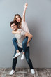 © Drobot Dean - Full length portrait of a joyful man carrying girlfriend