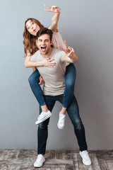 Wall Mural - Full length portrait of a cheerful man carrying girlfriend