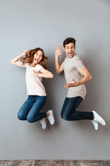 Poster - Full length portrait of a smiling young couple jumping