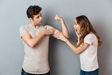 Canvas Print - Confident young man showing biceps to his amazed girlfriend