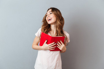 Canvas Print - Portrait of a pretty laughing girl holding book