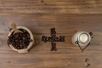 Wall Mural - Coffee bean grain ,bottle of milk and sack fabrice board on brown wood table background , include copyspace for add text or graphic in advertise or marketing content