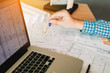 © wutzkoh - Architect working on blueprint in workplace with laptop and drawing compass.
