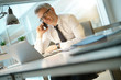 © goodluz - Businessman in office talking on smartphone