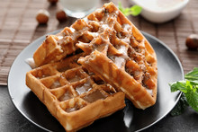 Tasty waffles and caramel topping on plate