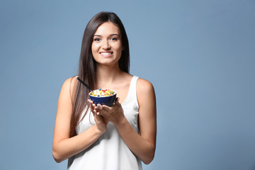 Wall Mural - Young woman eating oatmeal on light background