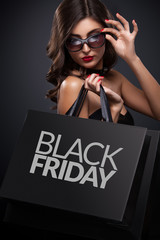 Shopping woman holding grey bag on dark background in black friday holiday