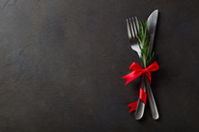 Festive Set Of Cutlery Knife And Fork With Red Satin Bow With Rosemary, Dark Stone Slate Background, Top View, Copyspace, Horizontal Image