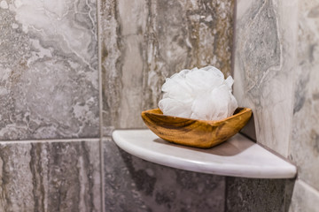 Closeup of staging shower pouf brush in modern stone grey bathroom in model home, apartment or house