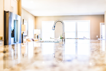 New modern faucet and kitchen room sink closeup with island and granite countertops in model house, home, apartment