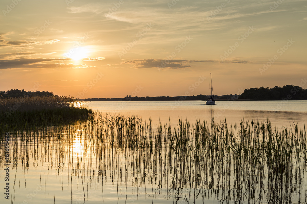 zdjęcie łódki w zachodzącym słońcu na jeziorze - obrazy, fototapety, plakaty 