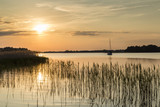 Fototapeta  - zdjęcie łódki w zachodzącym słońcu na jeziorze