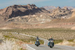 Two motorcycles travel along mountainous desert landscape 