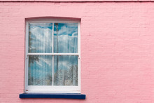 Victorian Window With White Wooden Sash, White Curtains And Blue Balcony On A Bright Pink Painted Brick Wall