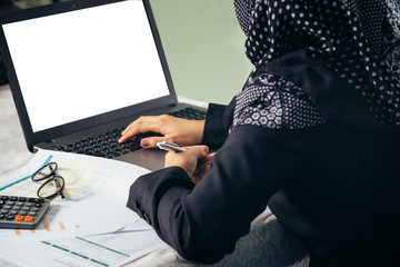 The backside of business muslim woman working on blank laptop display for editing.