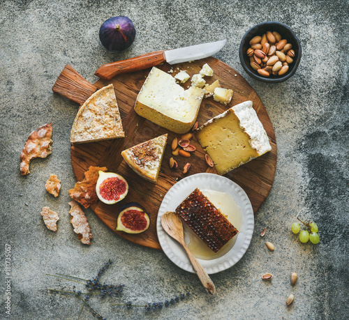 Photo Flat-lay of cheese platter with cheese assortment, figs, honey and nuts over grey concrete background, top view