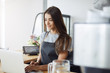 © Liubov Levytska - Portrait of young female coffee shop owner using a laptop waiting for her first customer early in the morning. Woman running her business.
