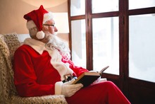 Santa Claus Reading Novel In Living Room During Christmas Time