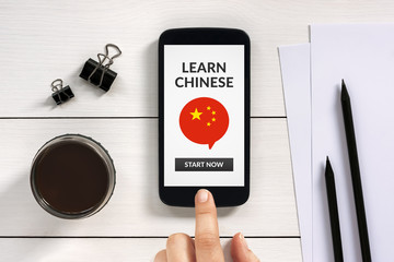 Wall Mural - learn chinese concept on smart phone screen with office objects on white wooden table. all screen co