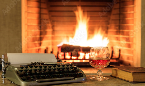 Glass Of Brandy And A Typewriter On Burning Fireplace Background