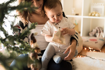 Mom and baby decorating the Christmas tree.