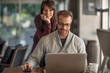 © Connect Images - Businesswoman and man looking at laptop at home desk