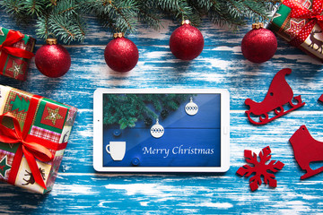 New year's background on a blue and white desk decorated with toys, presents, Christmas tree. Bright colored background symbolizes the new year celebration. Great useful template with a tablet.