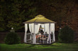 A beautiful gazebo with a table in the evening, autumn park is lit by a lamp.