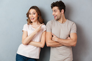 Wall Mural - Portrait of a smiling young couple pointing finger