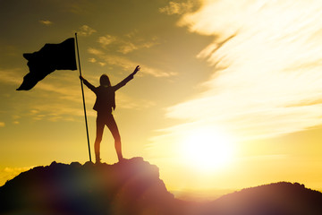 high achievement, silhouettes of the girl, flag of victory on the top of the mountain, hands up. a m
