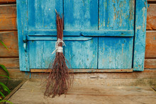 An Old Broom On The Background Of A Blue Antique Wooden Door